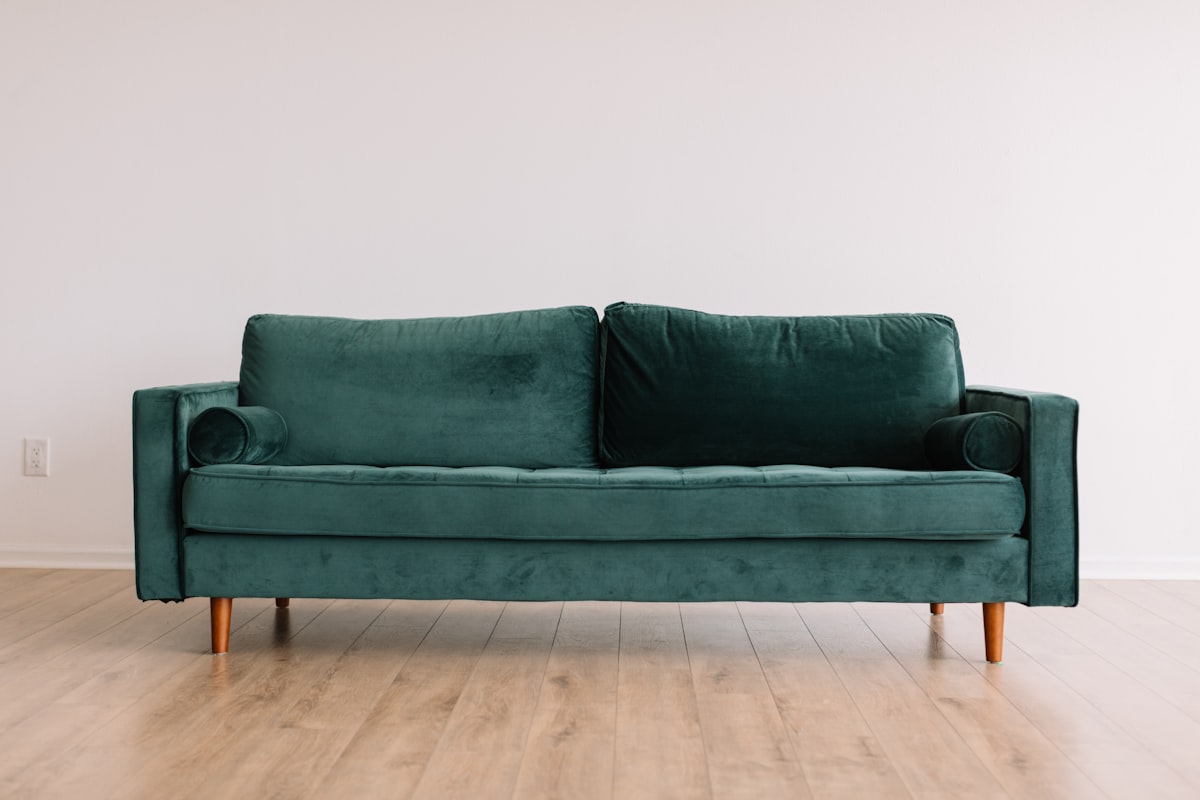 Sophisticated monochromatic living room with rich forest green walls, matching trim, and velvet sofa
