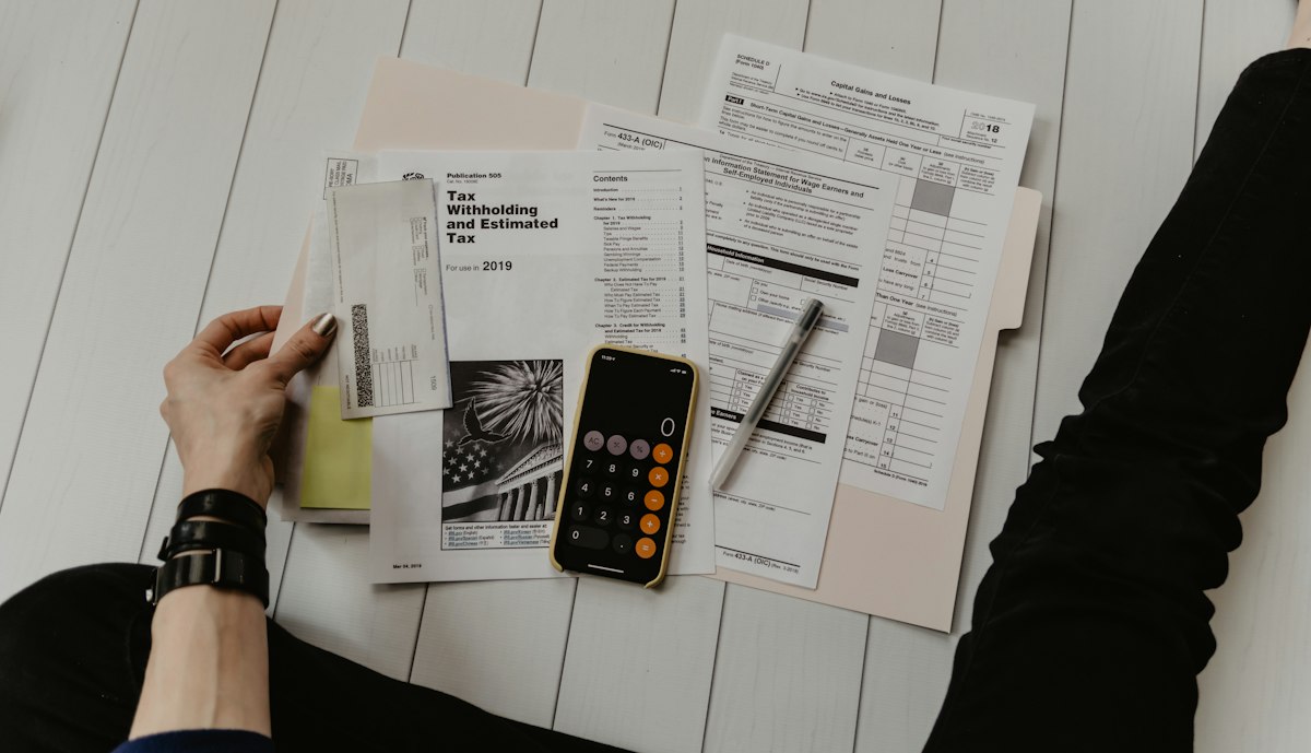 Mortgage financing documents, calculator, and financial balance ledger on wooden desk